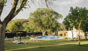 a pool in a yard with chairs and an umbrella at Camping Kikopark Rural in Villargordo del Cabriel +30 photos