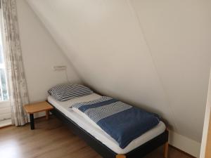 a small bed in a room with a white wall at Vrijstaande woning te Vlagtwedde in Vlagtwedde +5 photos