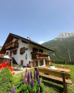 una casa in montagna con fiori in primo piano di Villa Rosa a Vigo di Fassa