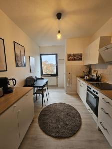 una cocina con armarios blancos y una mesa con alfombra en Moderne 2 Zimmer 70 qm Wohnung in Top Altstadtlage, en Coblenza