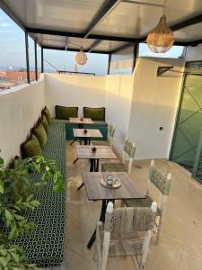 eine Terrasse mit Tischen und Stühlen auf einem Dach in der Unterkunft Habibi Riad&Hostel in Marrakesch + 35 Fotos