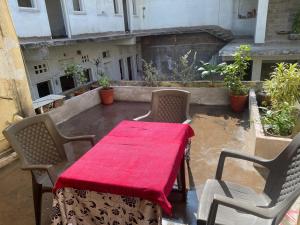 a table and chairs on a balcony with a red blanket at Tana Haveli Homestay udaipur in Udaipur