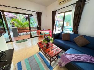 a living room with a blue couch and a table at Ao-Nang New! MATA Garden Bungalow-Apartments in Ao Nang Beach