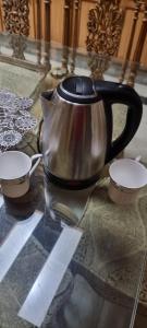 a tea kettle and two cups on a glass table at Sialkot International Airport Guesthouse in Sambriāl
