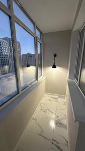 ein leerer Raum mit zwei Fenstern und einem Marmorboden in der Unterkunft 2-х комнатные апартаменты на Экспо in Astana