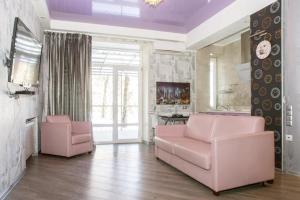 sala de estar con 2 sillas rosas y sofá en Apartments city center, en Járkov