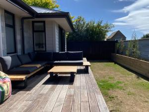 a patio with a couch and a table on a deck at Brand new on Arthur in Invercargill