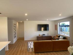 a living room with a couch and a tv on a wall at Brand new on Arthur in Invercargill