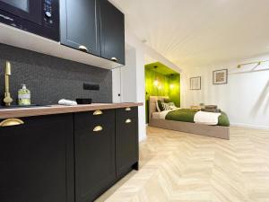 a kitchen with black cabinets and a bed in the background at Suite Émeraude centre ville in Sélestat