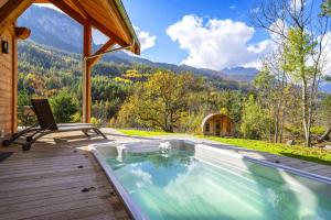 a pool on a deck with a chair and a house at Chalet Ecrin des Vignes in Les Vigneaux