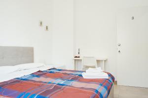 a white room with a bed with a colorful blanket at CIVICO 15 BED BREAKFAST in Mercato San Severino
