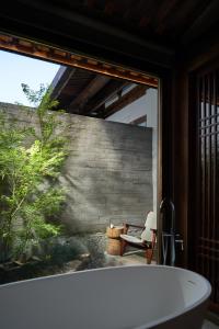 福州福州三坊七巷安民半舍文化酒店Fuzhou Sanfang Qixiang Anmin Banshe Cultural Hotel的带窗户的浴室里的浴缸