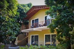 a yellow house with a balcony and trees at The Greenwich resort in Rāmnagar