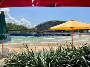 a swimming pool with an umbrella and a building at CBD Esplanade Location - Quiet & Comfortable in Darwin