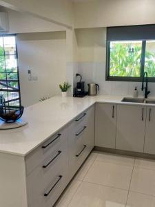 a white kitchen with a sink and a window at CBD Esplanade Location - Quiet & Comfortable in Darwin