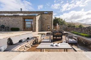 an outdoor patio with a fireplace and a stone building at Carden Laithe By Birch Stays in Skipton