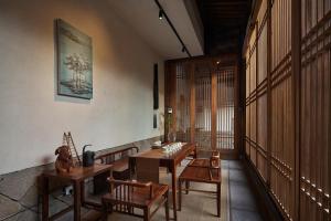 福州福州三坊七巷安民半舍文化酒店Fuzhou Sanfang Qixiang Anmin Banshe Cultural Hotel的大楼内带木桌和椅子的房间