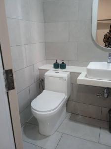 a white bathroom with a toilet and a sink at The Shore Seaview in Kota Kinabalu