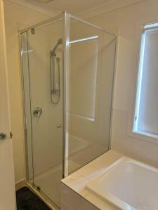 a bathroom with a glass shower with a sink at The Blissful Abode in Truganina +5 photos