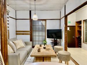 a living room with a couch and a tv at 桜木町 鶴 古民家の宿 in Nishi-hiranumachō