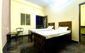 two beds in a room with a table and a chair at BSSN Guest House in Gwalior