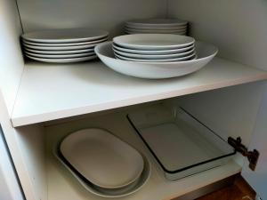 ein weißer Schrank mit Platten und Schalen auf einem Regal in der Unterkunft Moderno Atico Loft en Peñíscola Centro, cerca de la Playa y el Castillo Papa Luna in Peñíscola