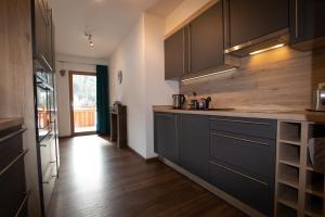 cocina con armarios negros y suelo de madera en Chalet Thierbach WILD019 FeWo-PLAN, en Thierbach