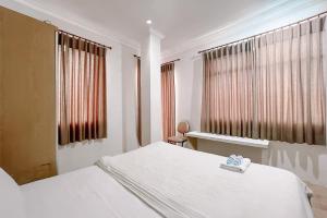 a bedroom with a white bed and two windows at Scala Inn By Helocus in Medan