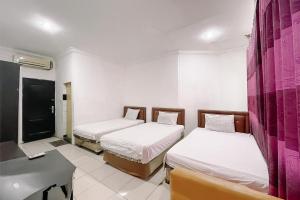 a room with two beds and a table and a desk at Scala Inn By Helocus in Medan +19 photos