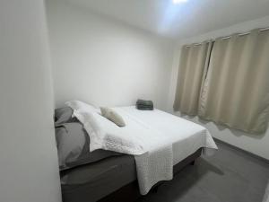a bedroom with a bed with a white blanket at Apartamento prox Outlet Campo Largo, BR e Hospitais, possui lava e seca in Campo Largo