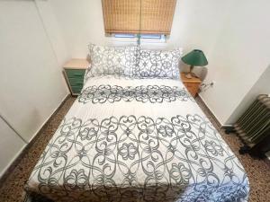 a bedroom with a bed with a white and black comforter at Apartamento Bonalba, Golf, Playas y Piscinas in Mutxamel