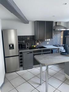 a kitchen with a stainless steel refrigerator and a table at Superbe séjour chez Renaud in Obenheim