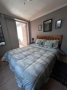 a bedroom with a large bed with a blue comforter at ChezBelle, self-catering 2 sleeper in Constantia with self check-in in Cape Town