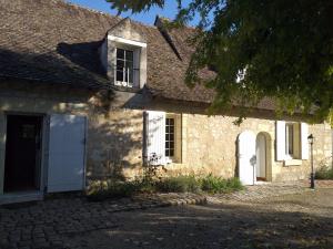 an old stone house with a white door and window at Au jardin de Florentine in Ingrandes-de-Touraine