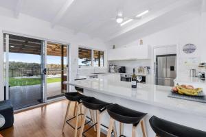a kitchen with a large white counter and stools at Beachfront Holiday Home Close to Airport in Lauderdale