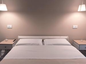 a bedroom with a white bed and two tables at Appartamento Dalì in Brescia +5 photos