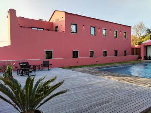 a red building with a swimming pool in front of it at Quinta da Casa Grande in Ponta Delgada