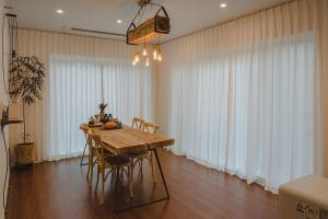 Un comedor con mesa y sillas de madera. en Jeju Stay Orot, en Jeju