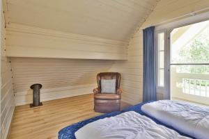 a bedroom with a bed and a chair and a window at Vakantiehuis De Hut in Oostkapelle +22 photos