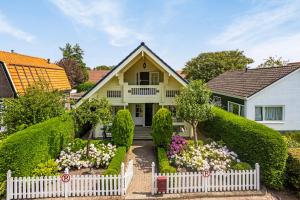 a white picket fence in front of a house with flowers at Vakantiehuis De Hut in Oostkapelle