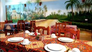 a dining room with a table and chairs and a painting at Cream Hostel in Luxor