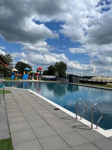 ein großes Schwimmbecken mit einem Spielplatz im Hintergrund in der Unterkunft Chalet-Frank in Lathum + 27 Fotos