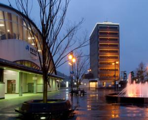a street with a building and a tree and a fountain at AZ Inn Higashi Omi Notogawa Ekimae in Higashiomi