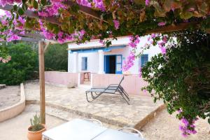 a chair sitting on a patio with purple flowers at CAN TONI DEN MESTRE in Cala Saona