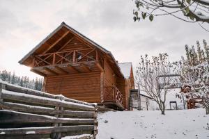 a wooden cabin in the snow with a fence at Затишна Домівка in Slavske