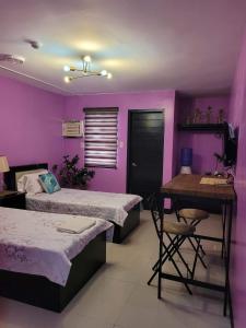 AltavasY&M Hotel Inn ALTAVAS AKLAN的紫色客房配有两张床和一张书桌