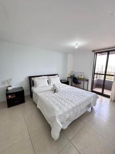 una camera da letto bianca con un grande letto con lenzuola bianche di Resort Paraiso do Atlântico - Beira Mar pé na areia a Cabedelo