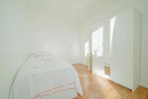 a white bedroom with a bed and a dresser at Appartement familial - proche Paris in Alfortville