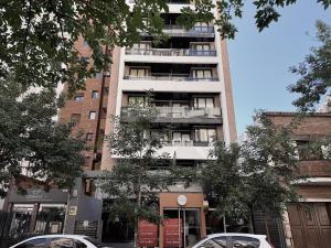 zwei Autos, die vor einem hohen Gebäude geparkt sind in der Unterkunft Apartamento Obispo Trejo, Nueva Cordoba in Cordoba