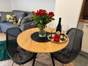 a wooden table with a vase of flowers and wine glasses at Ami Luxury Residence VI CENTRUM - parking- in Iława +7 photos